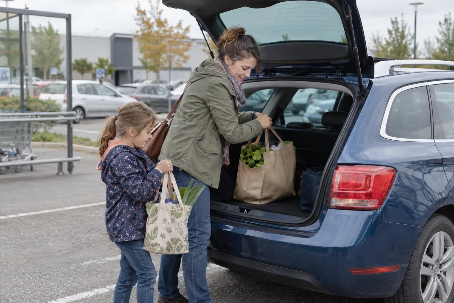 Une mère et son enfant rangent leurs courses dans la voiture familiale